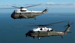 A VH-3D (top)  and a VH-60N Executive Transport Helicopter over water.